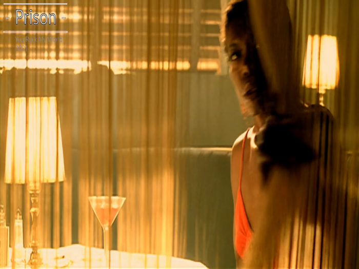 Kurzfilm You Rock my World von 2001. In einer Bar schiebt eine am Tisch sitzende Frau den Fadenvorhang zur Seite, um dem Auftritt des King of Pop zuzusehen. Der Fadenvorhang wirkt wie Gitterstäbe.
